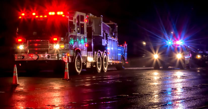 fire truck and police car parked with headlights and light bars illuminated