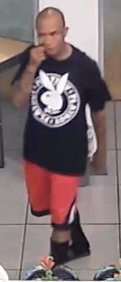 Photo of suspect wearing a black t-shirt with a Playboy bunny print on it and red shorts