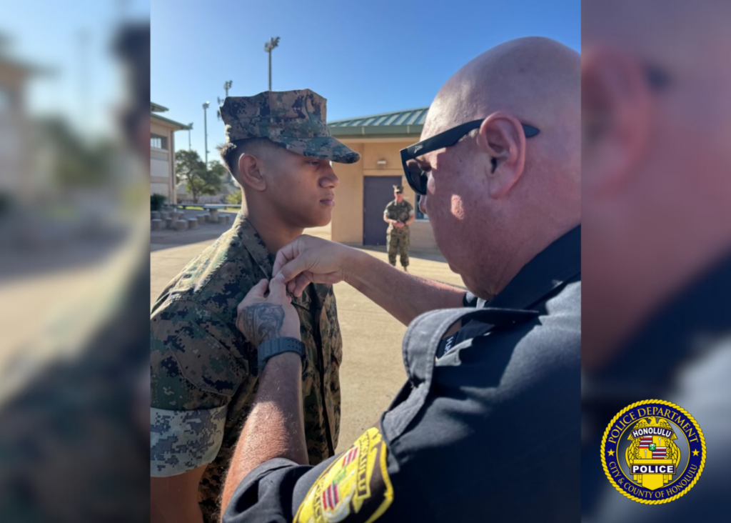 Half-body photos of a Honolulu Police Department School Resource Officer (SRO) and a Kapolei High School JROTC student and cadet. The SRO is attired in his uniform and the cadet is attired in shades of green camouflage uniform. The SRO is placing a pin on the cadets uniform.