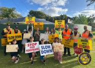 Police officers and elementary school students hold traffic safety signs promoting safe driving and pedestrian awareness.