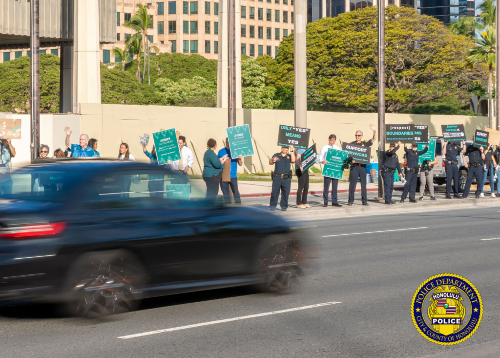 In front of the Hawaii State Capitol, HPD officers in uniform and community members holding signs in observance of Sexual Assault Awareness Month.