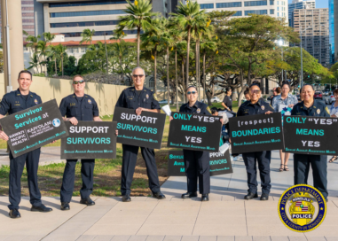 In front of the Hawaii State Capitol, six HPD officers in uniform holding signs in observance of Sexual Assault Awareness Month.