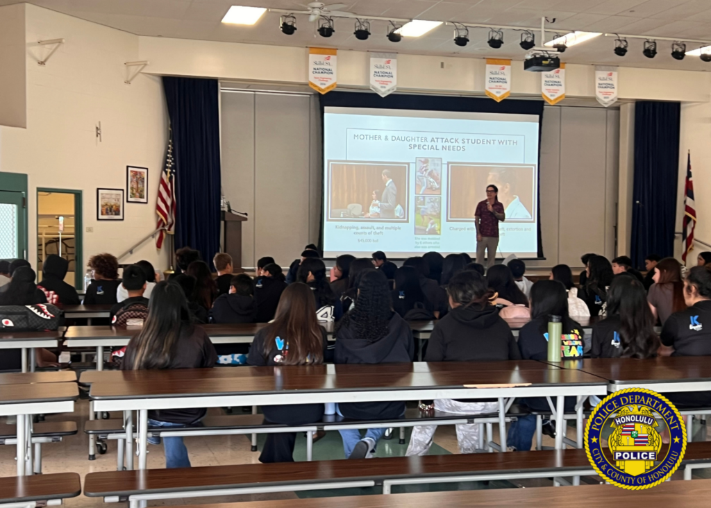 A community member speaks to students while a presentation is displayed on a projector.