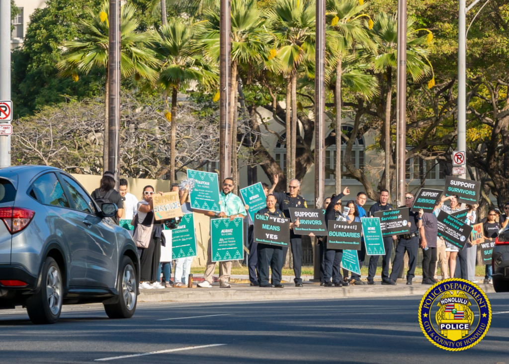 In front of the Hawaii State Capitol, HPD officers in uniform and community members holding signs in observance of Sexual Assault Awareness Month.