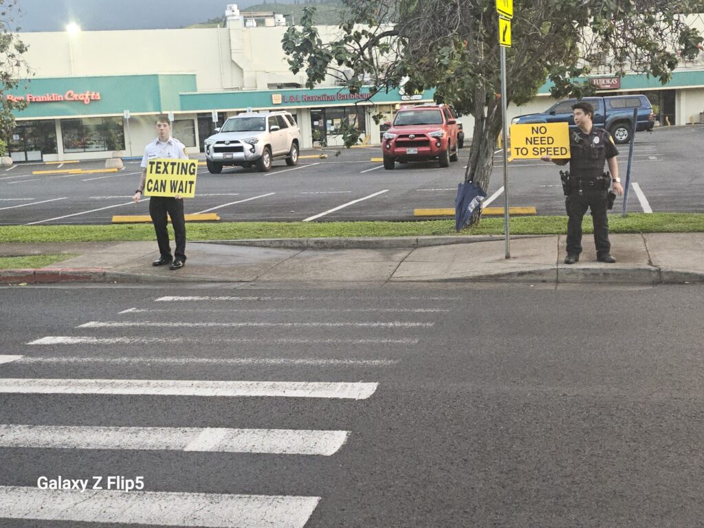 HPD Officer sign-waving to promote traffic safety at school.