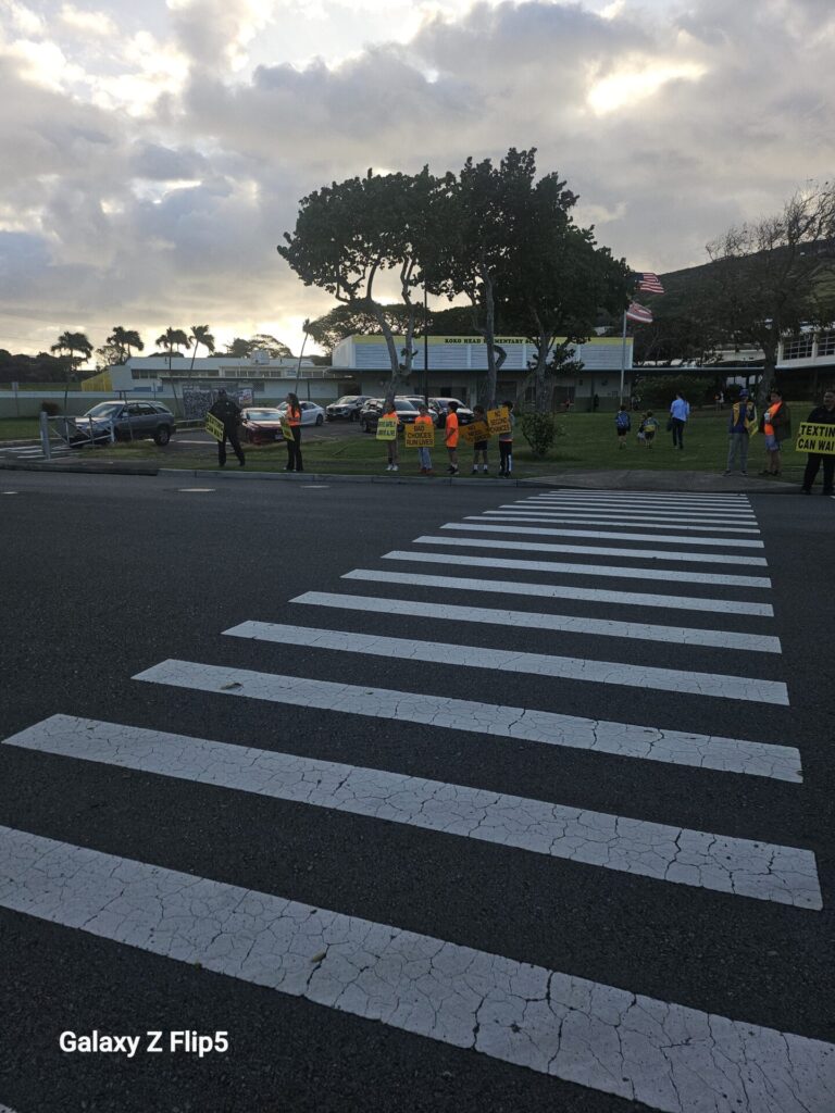 HPD Officers and students sign-waving to promote traffic safety at school.
