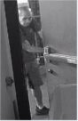 Unknown bald male suspect with tattoos on bicep and leg shown on surveillance camera