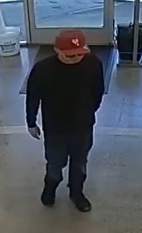 Unknown male wearing a flat bill baseball cap and dark sunglasses indoors as shown on surveillance camera