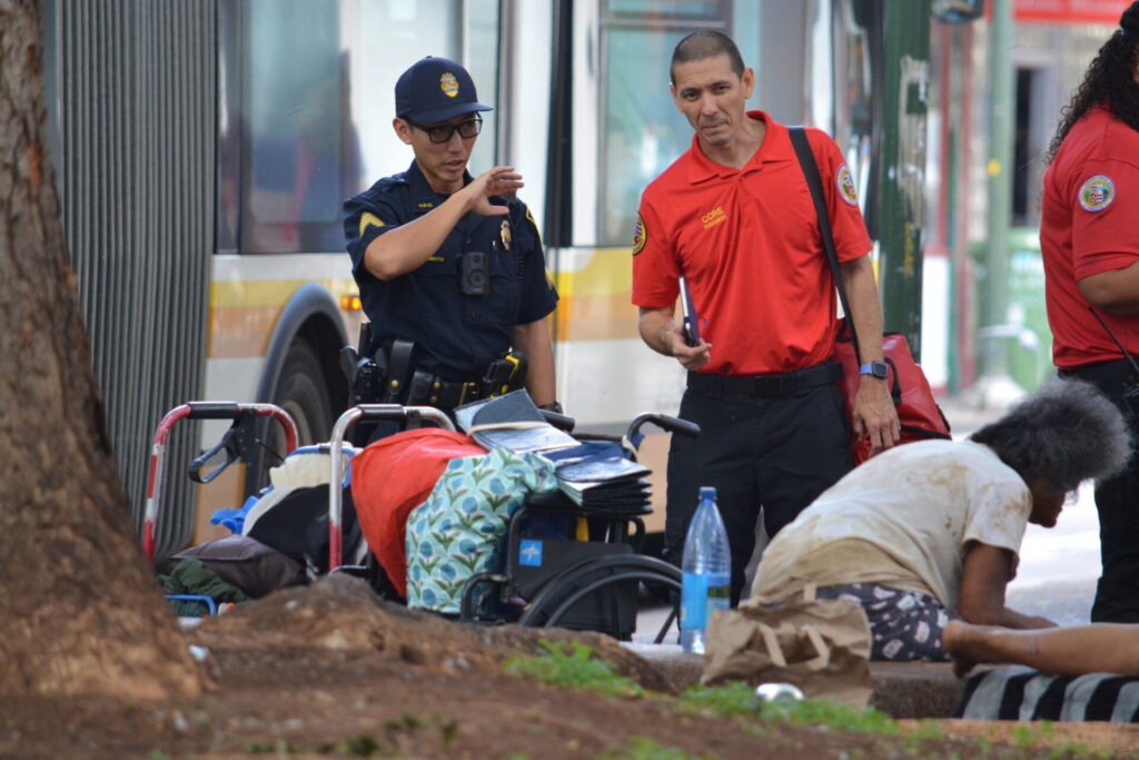 HPD_Sgt. Matsumoto and CORE District Chief Jon Kurosu Sgt. Corbin Matsumura and CORE District Chief Jon Kurosu are working together to intervene with a homeless individual at a bus stop in Honolulu.