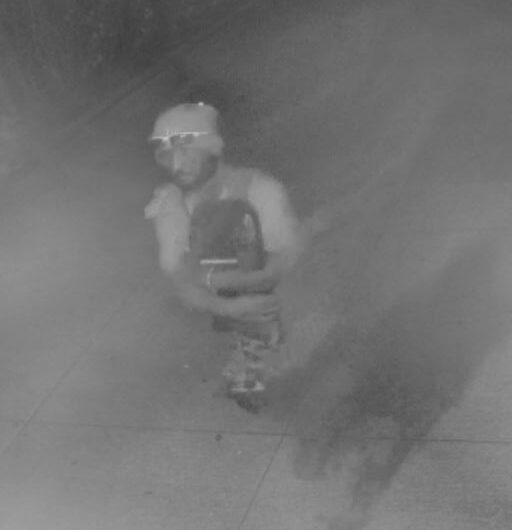 Unknown Micronesian male suspect wearing a beanie and carrying a skateboard as shown on surveillance camera