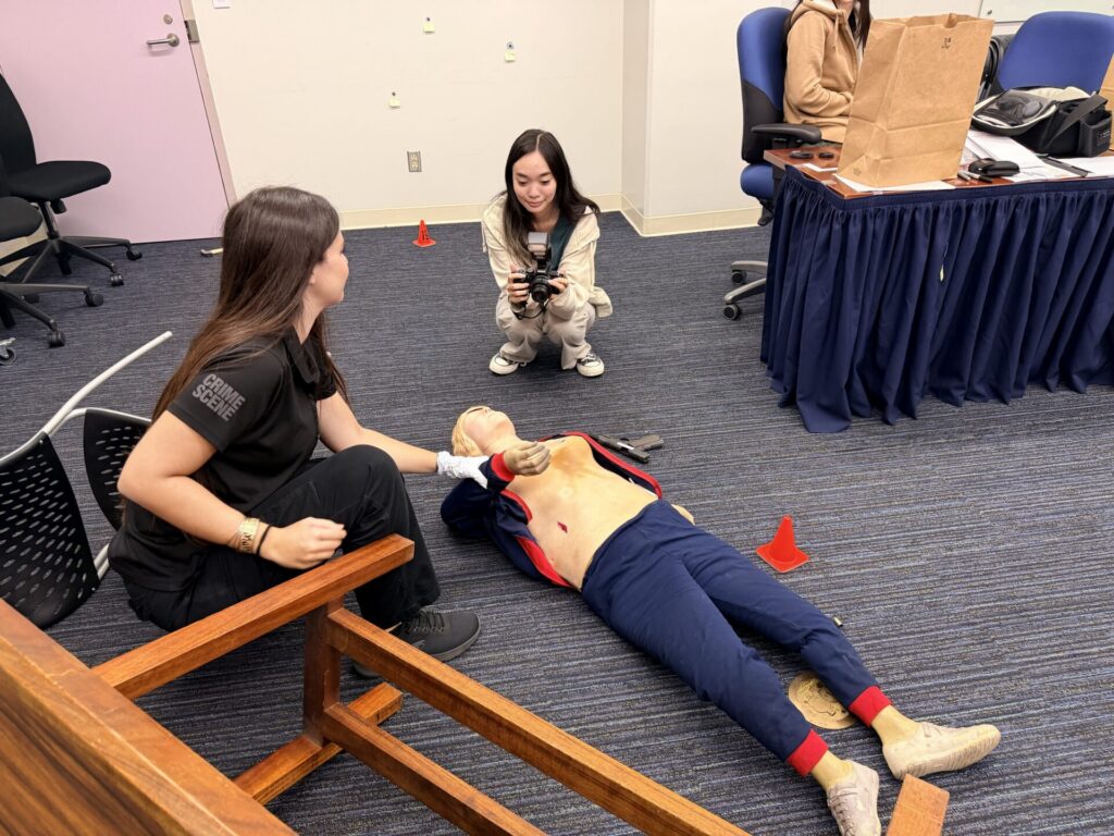 SIS Intern Leila Takamatsu practices taking photos at a mock crime scene