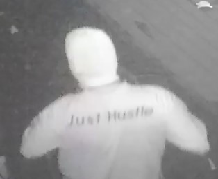 Unknown male suspect with a unique shirt with words Just Hustle printed on the back as shown on surveillance camera