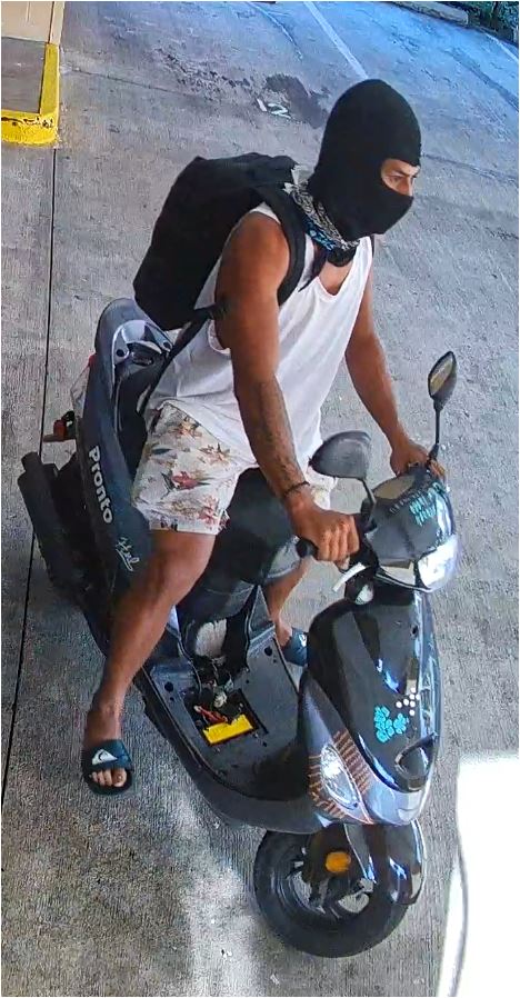 Unknown male suspect on a black moped with stickers on the front above and below the headlight as shown on surveillance camera