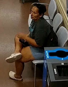 Unknown female suspect carrying a slingbag with sunglasses on her head and hair pulled back in a bun as shown on surveillance camera