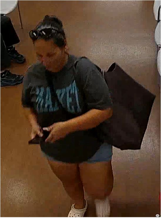 Unknown female suspect carrying a slingbag with sunglasses on her head and hair pulled back in a bun as shown on surveillance camera