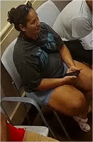 Unknown female suspect carrying a slingbag with sunglasses on her head and hair pulled back in a bun as shown on surveillance camera