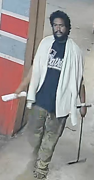 Unknown barefoot male suspect wearing a bath towel around his neck and medical wristband as shown on surveillance camera