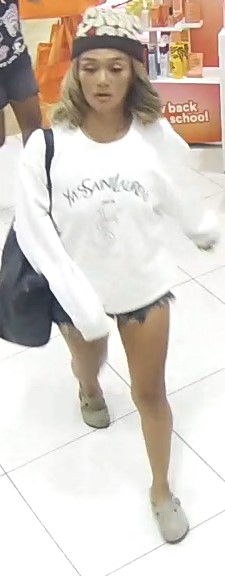 : Unknown female wearing a Yves Saint Laurent sweatshirt and blue denim cutoff shorts as shown on surveillance camera