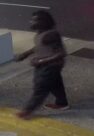Unknown male suspect possibly wearing a gold watch or bracelet on his left wrist, long pants, and a t-shirt under a tank top as shown on surveillance camera